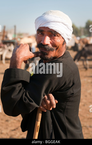 Egiziano Turbaned uomo con i baffi completo e della canna da zucchero in un mercato di cammelli lungo il Nilo. Foto Stock