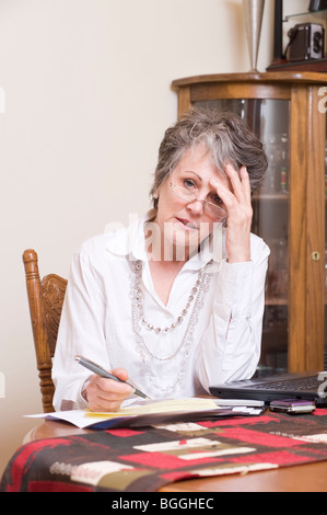 Active senior donna paga le bollette di casa online utilizzando un computer portatile. Immagine è il modello / proprietà rilasciato. Foto Stock