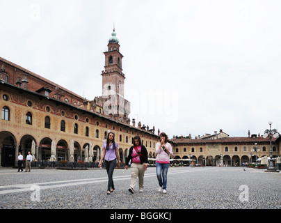 Giovani donne con del Bramante torre sul Castello Sforzesco in Piazza Ducale di Vigevano Lombardia Italia con portici o portaci Foto Stock