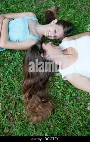 Madre e figlia insieme giacente al di fuori in erba, Hawaii Foto Stock