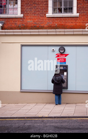 Una donna riceve denaro contante dai bancomat speedbank macchina in Norwich, Norfolk, Regno Unito Foto Stock