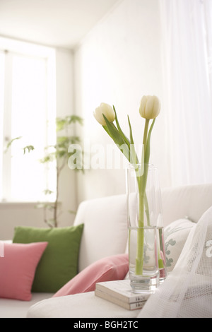 Tulipani bianco in un vaso accanto a un divano Foto Stock