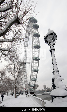 The London Eye on the South Bank in the snow, view towards Houses of Parliament and Westminster Bridge Foto Stock
