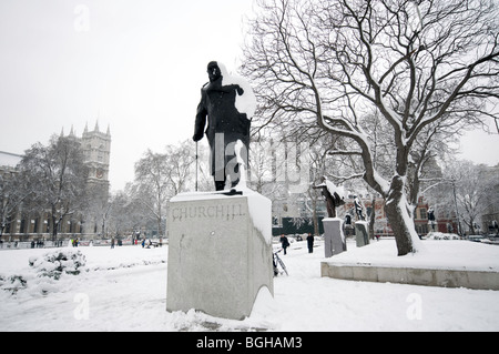 Winston Churchill la statua sulla piazza del Parlamento a Londra centrale coperto di neve, la Cattedrale di Westminster in background Foto Stock