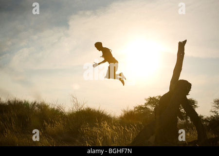 I Boscimani uomo tribali di saltare fuori di alberi caduti, Deserto Kalahari, Namibia Foto Stock