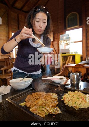 Okonomi yaki. Stile giapponese gustosi pancake cotti su una piastra calda. Giappone Foto Stock