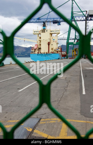 Piccoli container ormeggiata lungo la banchina del terminal container, visto attraverso la recinzione di sicurezza, Lyttelton, Nuova Zelanda Foto Stock