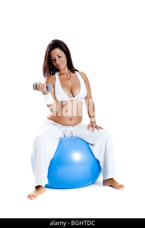 Bella donna incinta facendo esercizi su una sfera di fitness Foto Stock
