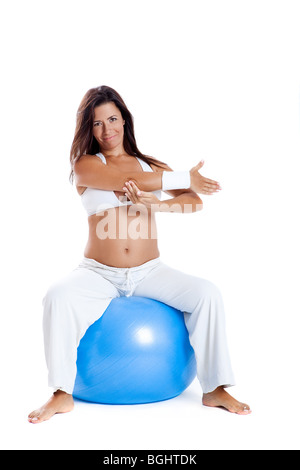 Bella donna incinta facendo esercizi su una sfera di fitness Foto Stock