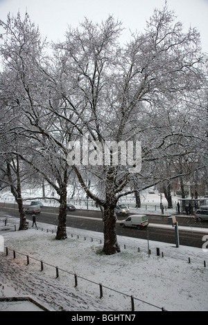 La neve cade su Clapham Common Southside Rd - un po' di traffico Foto Stock