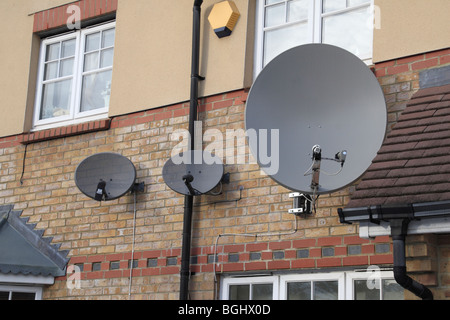 Una linea di tre antenne satellitari su proprietà in Hounslow West London, Regno Unito. Foto Stock