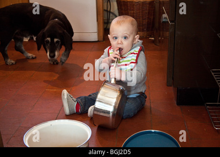 Baby boy (otto mesi) giocando con pentole e padelle sul pavimento della cucina. Foto Stock