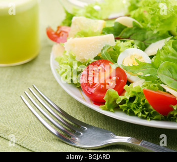 Insalata fresca con pomodoro e uova di quaglia in una ciotola bianco su una tovaglia verde Foto Stock