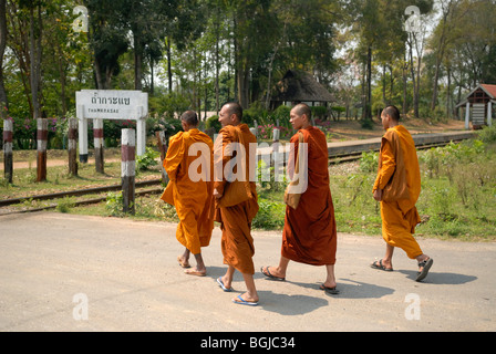 Quattro i monaci buddisti a piedi lungo una strada, Thamkrasae Bridge, distretto di Kanchanaburi, Thailandia Foto Stock