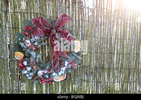 Natale decorazione esterna corona appeso stick recinto nel paesaggio formato orizzontale con il sole che splende da dietro Foto Stock