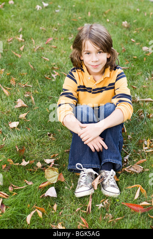 Ragazzo seduto sull'erba Foto Stock