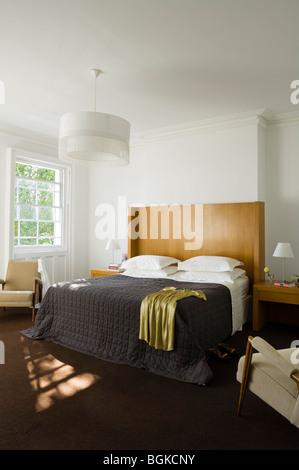 Letto matrimoniale con testata in legno e copriletto trapuntato in bianco  camera da letto con grande ombra leggera Foto stock - Alamy