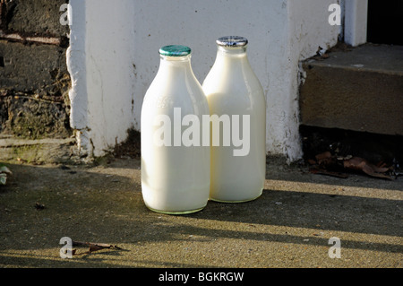 Due bottiglie di latte da pinta a portata di mano, una con tappo verde e una argento, Londra Inghilterra Gran Bretagna, Regno Unito, rifiuti zero Foto Stock