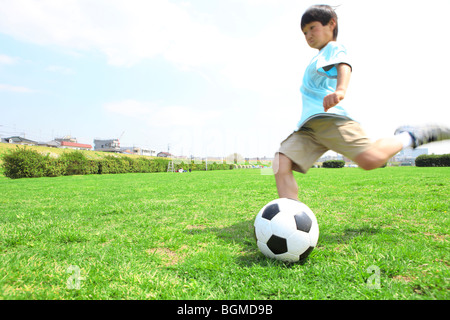 Ragazzo giovane calci palla calcio sul campo. Futako-tamagawa Setagaya-ku Prefettura di Tokyo Giappone Foto Stock