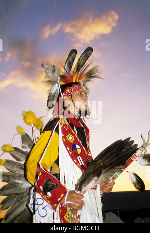 Lakota Sioux ragazzo adolescente vestito in tradizionale cuccia wow regalia tiene aquila ala fan e aquila artiglio dance stick, Pine Ridge Reservation, South Dakota Foto Stock