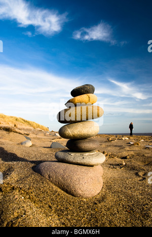 Una torre in pietra costruito sulla spiaggia al punto di disprezzare il vecchio faro visibile in background Foto Stock