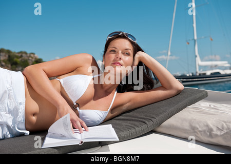 Donna attraente a prendere il sole sulla barca di lusso libro in bikini Foto Stock