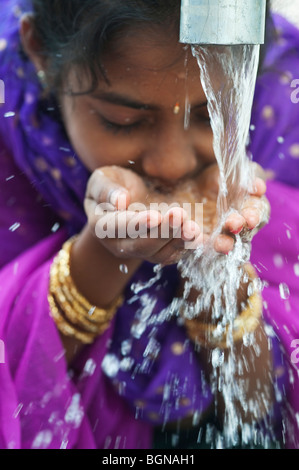 Ragazza indiana di bere da una pompa di acqua. India Foto Stock