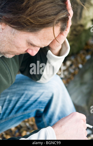 Un colore foto ritratto di un depresso e ha sottolineato uomo maturo di fumare una sigaretta. Foto Stock