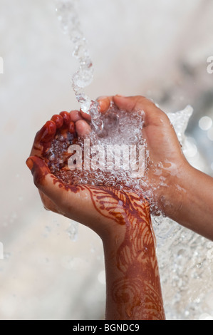 Indian childs mani a tazza la cattura di acqua versata. India Foto Stock