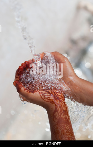 Indian childs mani a tazza la cattura di acqua versata. India Foto Stock