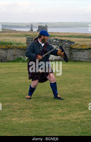 Un uomo in costume storico re-decreta battaglie storiche al Sinclair raccolta, Noss, vicino a Wick, Scozia. Foto Stock