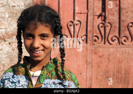 Giovani schoolgirl egiziano che pongono di fronte a un cancello di ferro che rispecchia la sua trecce. Foto Stock