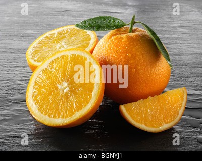 Intero e tagliare le arance fresche con foglie Foto Stock