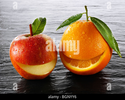 Smiley arancione e Apple su sfondo nero Foto Stock