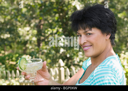 Ritratto di una donna matura con in mano un bicchiere di margarita e sorridente Foto Stock