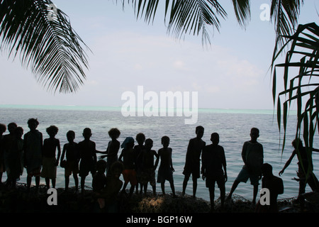 I bambini giocano sulle mura sul mare, costruita a frenare il processo di erosione del terreno da parte delle onde, Puil Isola Carteret Atoll, Papua Nuova Guinea Foto Stock