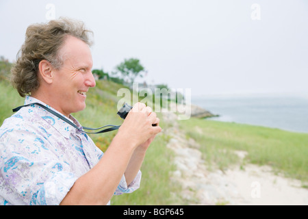 Profilo laterale di un uomo maturo tenendo un paio di binocoli Foto Stock