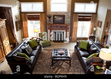 Country living room scuro con divani in pelle marrone e verde poltrona, caminetto e TV autoportante armadio Foto Stock