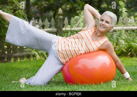 Ritratto di una donna matura esercitando con una sfera di fitness Foto Stock