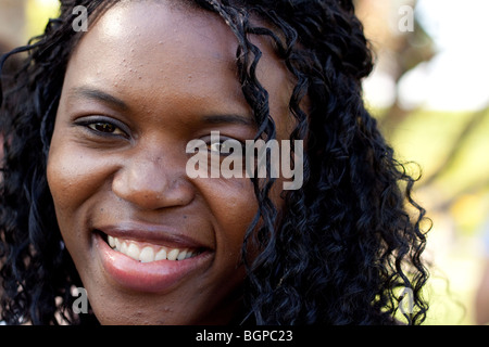 Una donna nera sorride e guarda la telecamera Foto Stock
