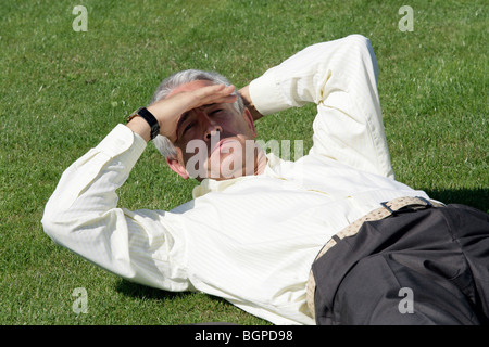 Coppia sconsolato imprenditore sdraiati sull'erba schermare gli occhi dalla luce solare Foto Stock