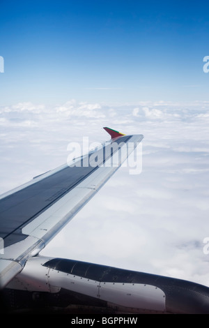 Ala di aeroplano come visto dalla finestra che mostra nuvole e cielo blu Foto Stock