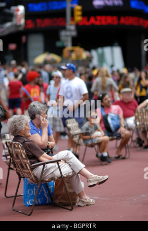 I turisti si prendono una pausa dalle visite turistiche nel prato sdraio che sono ora presenti in tutta Times Square. Foto Stock