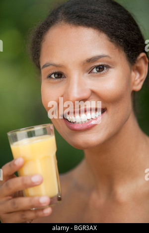 Primo piano della giovane donna di bere il succo di arancia in ambiente esterno. In verticale incorniciata shot. Foto Stock