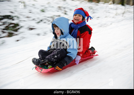 Due giovani felici di spensierata boys Kids Bambini in slittino sulla neve, gennaio 2010, Ceredigion, Wales, Regno Unito Foto Stock