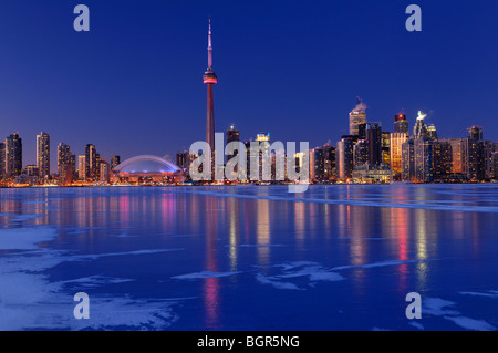 Ghiaccio congelato coperto lago Ontario riflette le luci della città di Toronto skyline al tramonto in inverno Foto Stock