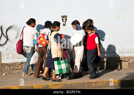 Due gruppi di donne messicane con bambini tenta di passare tra di loro su un marciapiede stretto nella città di Oaxaca Messico Foto Stock