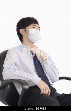 Giovane uomo di toccare la gola e indossando maschera chirurgica Foto Stock