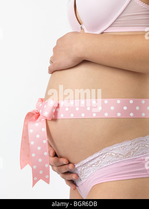 Donna incinta con un fiocco rosa sul suo ventre Foto stock - Alamy