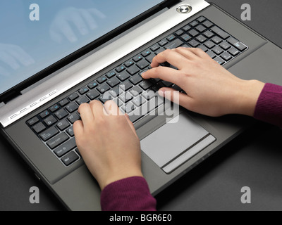 Donna digitando su un laptop computer tastiera Foto Stock